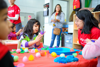 A child playing play dough with teacher in a classroom. 