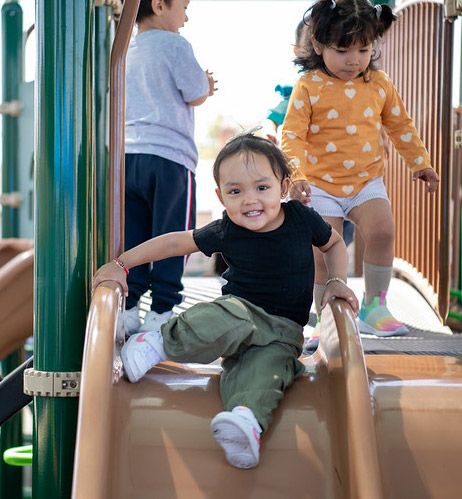 A child smiling and going down the slide.