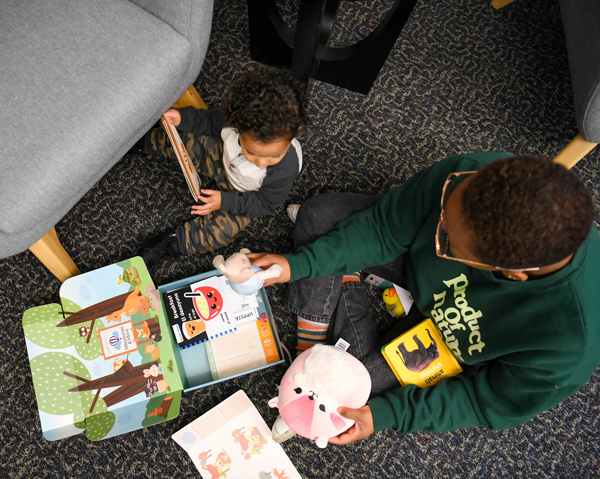 A mother and son opening a play kit of different toys. 