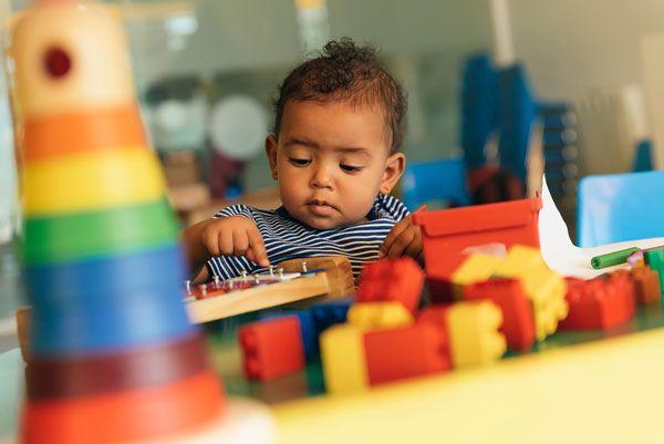 Happy baby playing with toy blocks and legos.